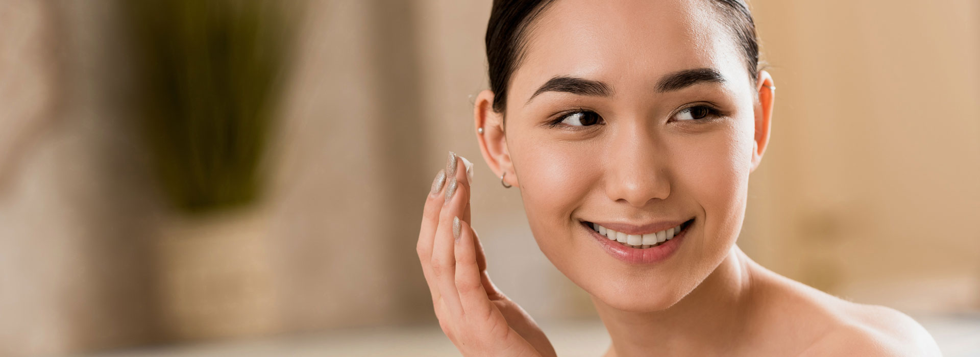 Attractive asian woman applying cosmetic cream